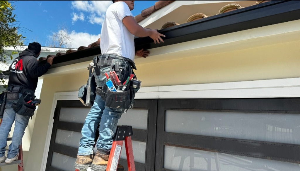 Crew installing rain gutters on residential home