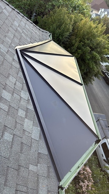 Decorative two-tone metal bay window roof accent over composition shingle
