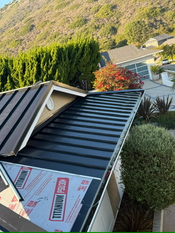 Standing seam metal roof installation in progress with underlayment and skylight
