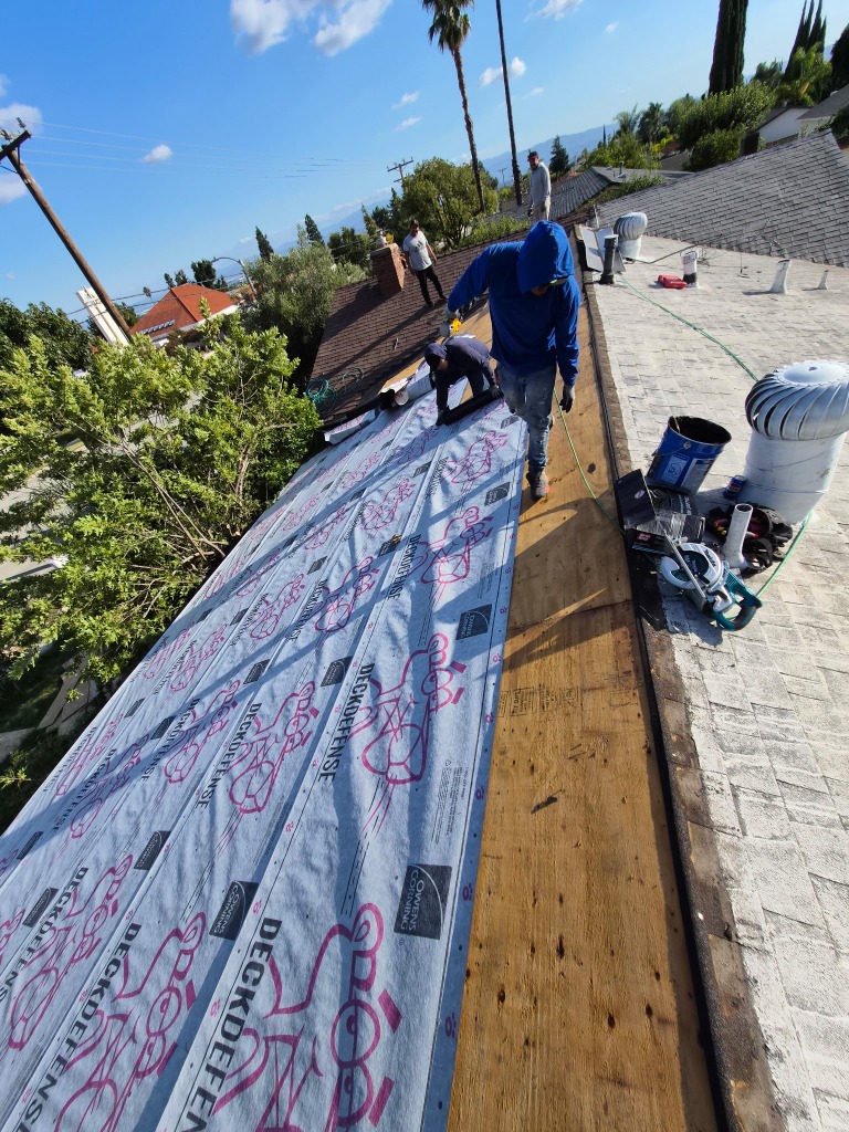 Crew laying roof underlayment during re-roof